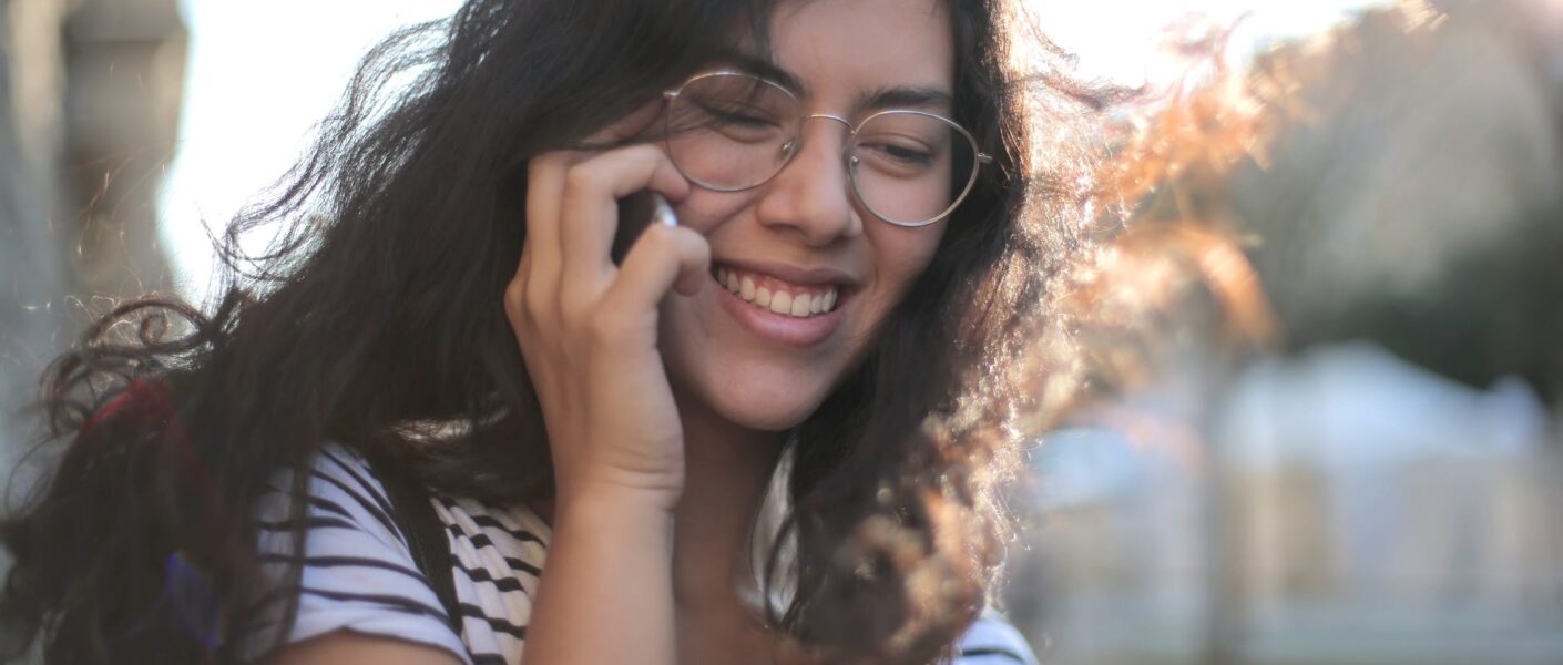 cheerful young woman making phone call on street